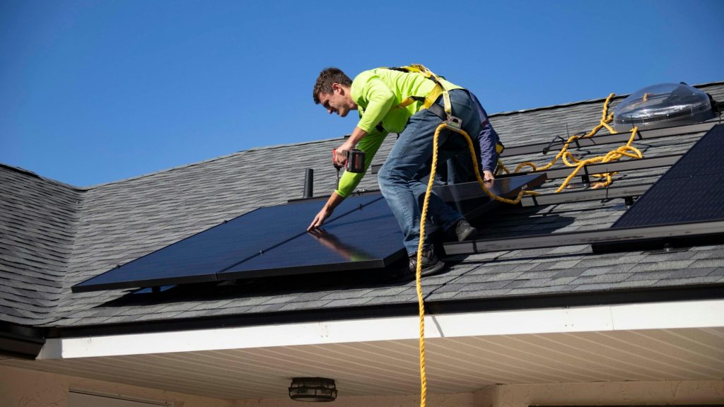 Technician installing solar panels on a roof